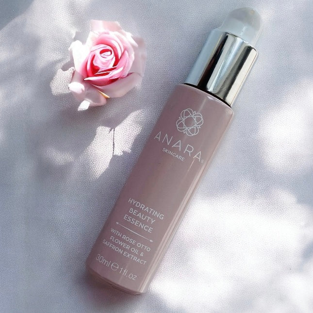 Anara Skincare Hydrating Beauty Essence in the sunshine with a pink rose