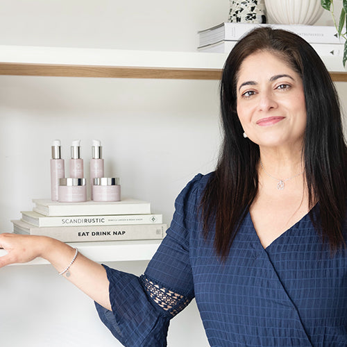 Arati Nar, Founder of Anara Skincare, standing in a relaxed pose in front of the Anara Skincare range.
